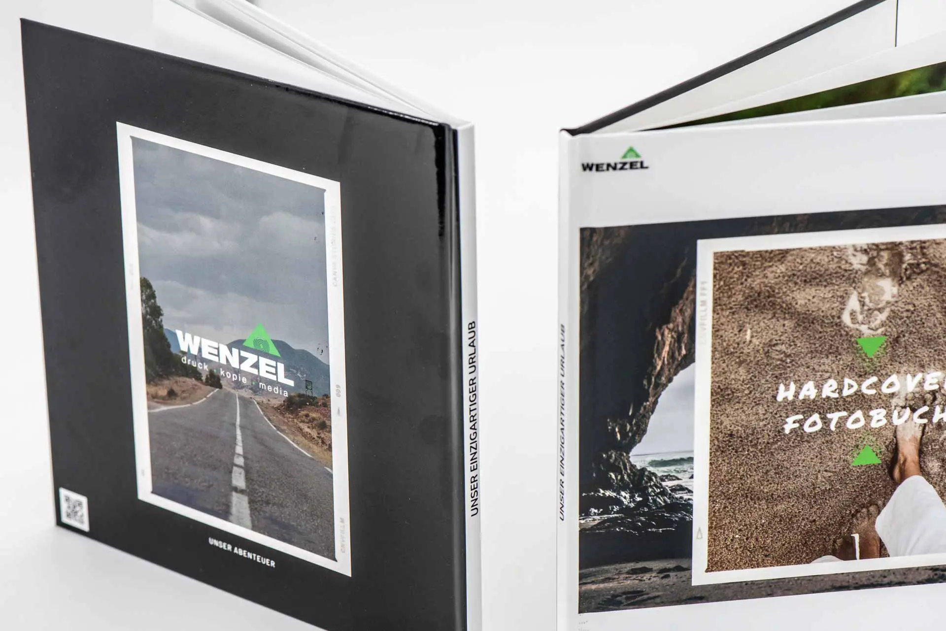 Zwei aufgeklappte Hardcover-Fotobücher mit individuellem Cover-Design, produziert von der Druckerei Wenzel