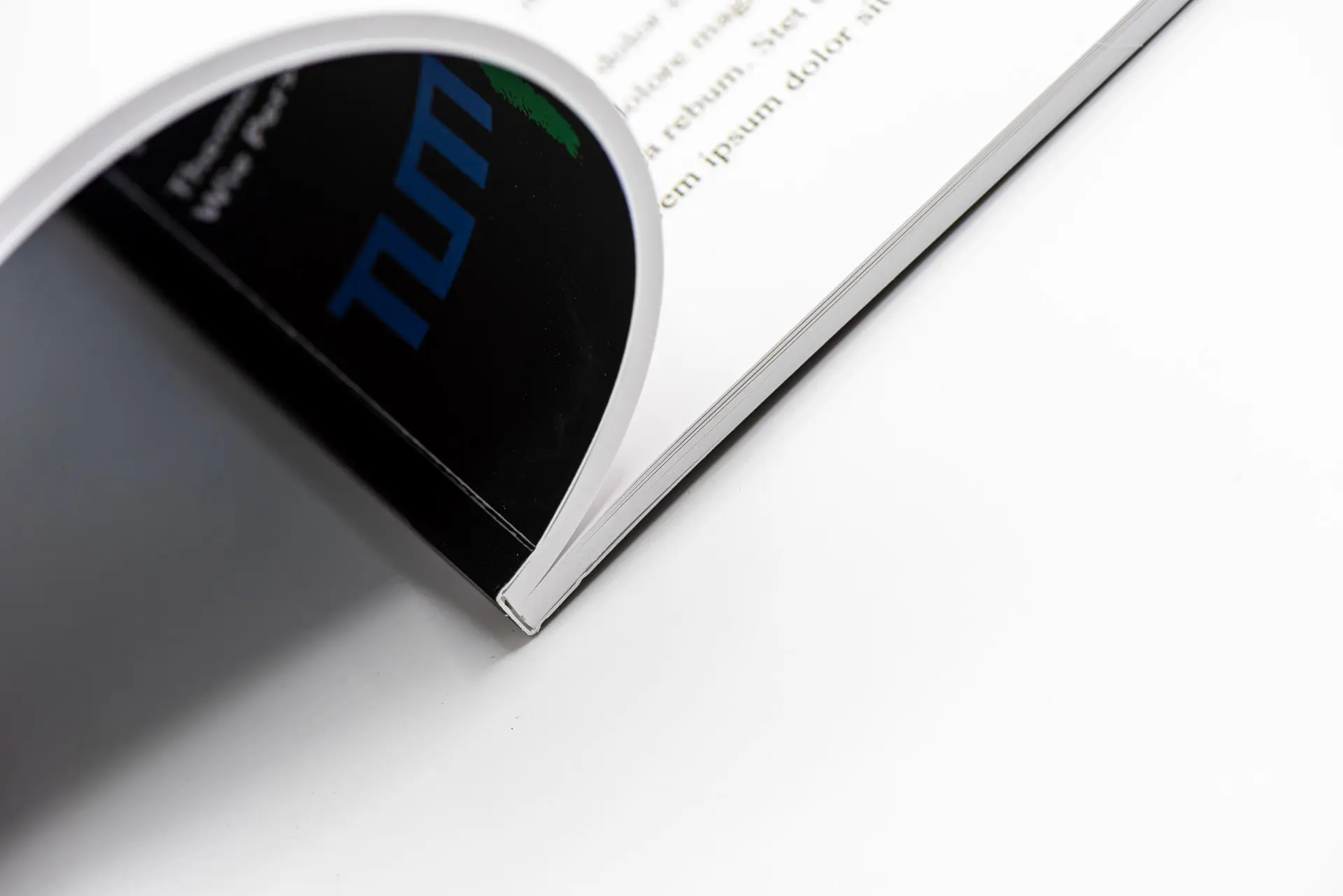Nahaufnahme einer Softcover-Bindung mit aufgeschlagenem Umschlag und TUM-Logo