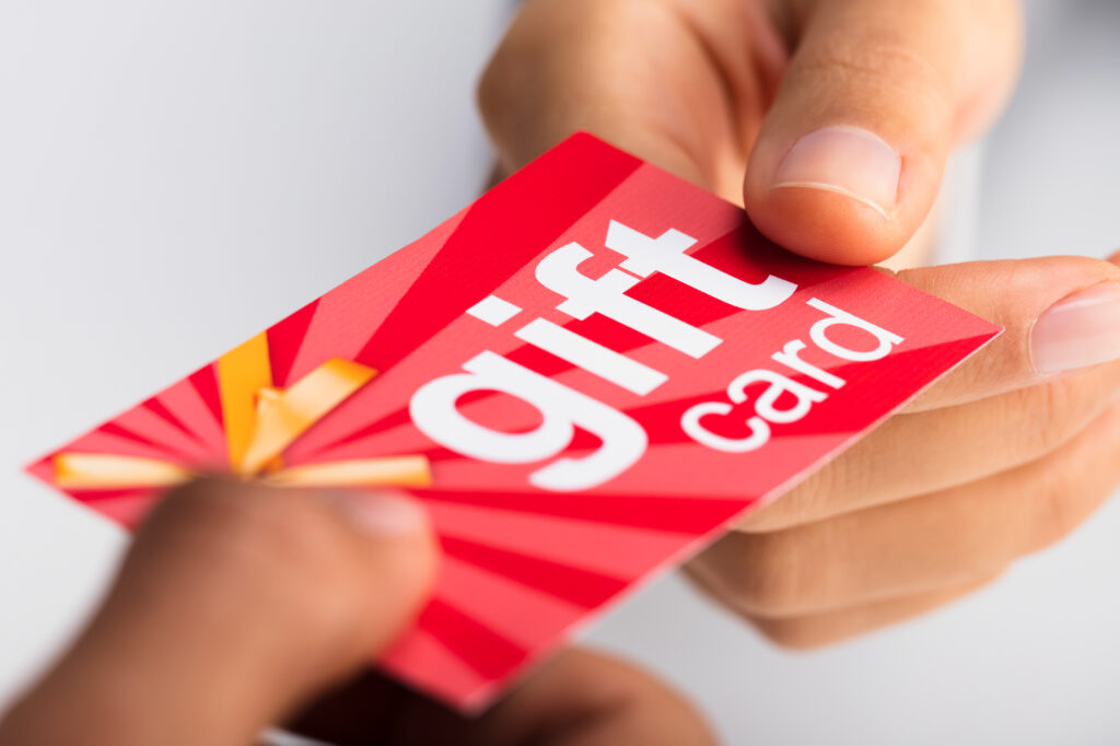 Hand überreicht eine farbenfrohe Geschenkkarte – ideal für Gutscheine und Coupons im Einzelhandel oder der Gastronomie.